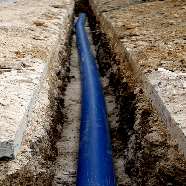 Un tuyau bleu enfoui dans le sol, illustrant l'installation d'un drain français.