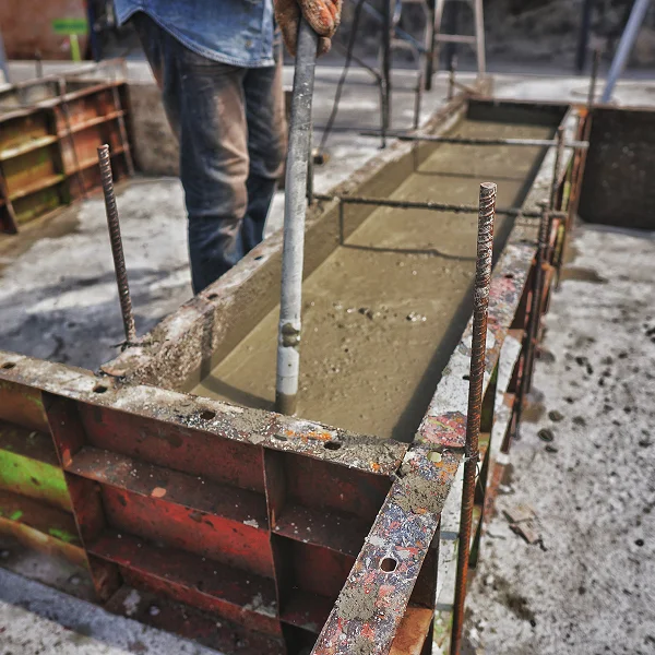 Un homme verse du béton dans un bloc de béton lors de travaux de terrassement.